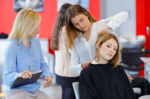 A cosmetology instructor helping a student to master a skill