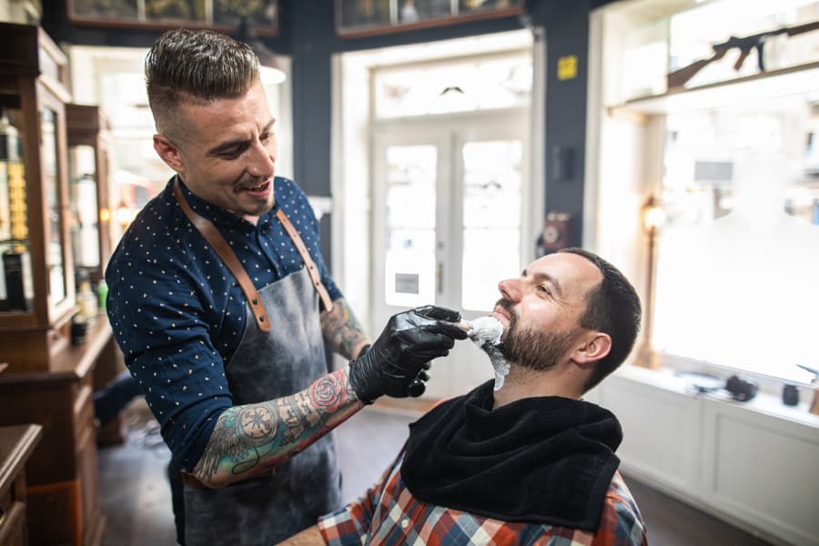 A barber puts lather on a man’s face