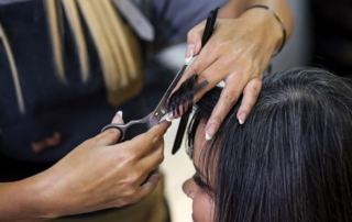 Cosmetology student cutting dark haired woman's hair